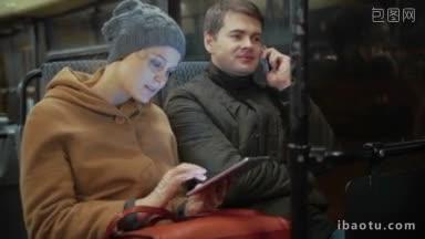 公交车上的年轻人，女人在用<strong>平板电脑</strong>，男人在晚上的旅行中打电话